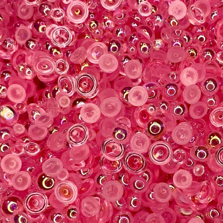 A close-up view of pink transparent iridescent acrylic pearls arranged to form a bubble pattern.