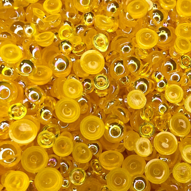 A close-up view of a honey-colored transparent iridescent bauble embellishment mix from Trinity Stamps.