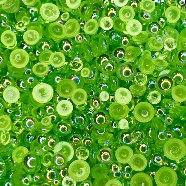 A close-up view of Sour Apple Bubbles embellishment mix featuring transparent iridescent green baubles.