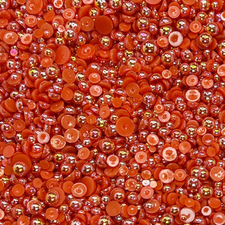 A close-up view of cherry red flat-back acrylic pearls of various sizes, intended for crafting and embellishment purposes.