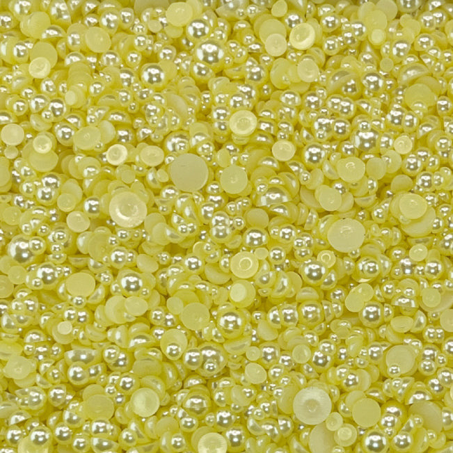 A close-up view of yellow flat-back acrylic pearls intended for crafting and embellishment purposes, with the text 'LEMON MERINGUE ACRYLIC FLAT-BACK BAUBLES EMBELLISHMENT MIX' displayed.