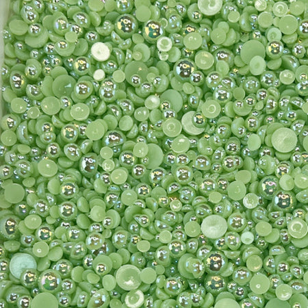 A close-up view of shiny sage green flat-back acrylic pearls of various sizes, intended for crafting purposes.
