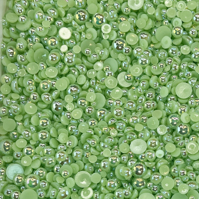A close-up view of shiny sage green flat-back acrylic pearls of various sizes, intended for crafting purposes.