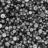 A close-up of various sizes of flat-back acrylic pearls, predominantly black in color, arranged in overlapping rows.