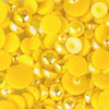A close-up of yellow acrylic flat-back baubles embellishments in a mix of sizes, with the brand's website address visible.