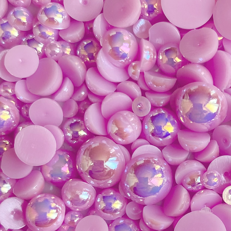 A variety of purple flat-back acrylic baubles in a plastic storage box with transparent iridescent finish.