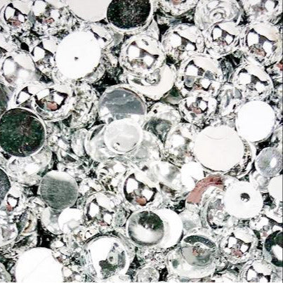 A close-up view of flat-back round resin stones in silver color, used as embellishments.